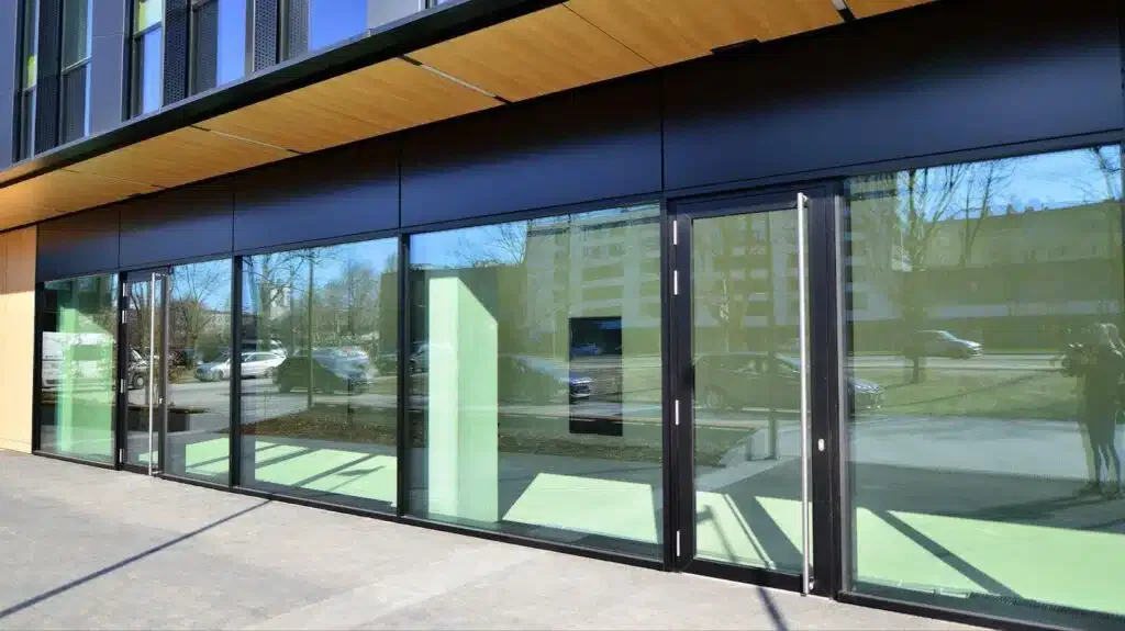 A modern building featuring large glass doors and windows reflecting natural light