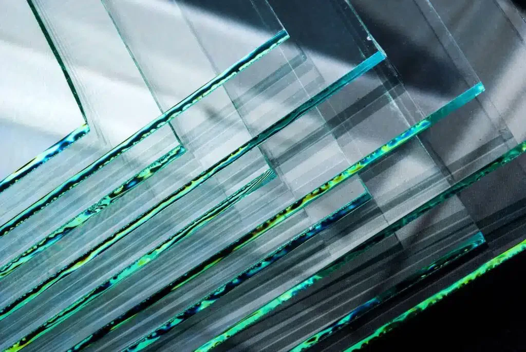 A stack of glass sheets featuring intricate green and blue lines, showcasing a blend of colors and transparency