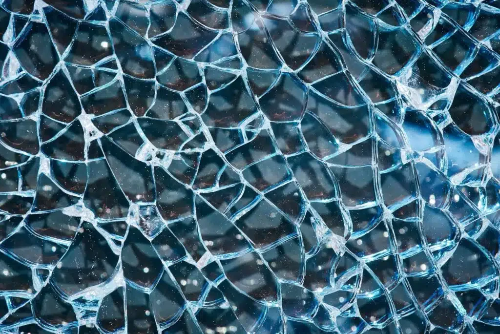 Detailed close-up of a cracked glass, showcasing complex patterns and light reflections