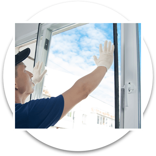 A man in gloves and a hat cleaning a window with a squeegee.