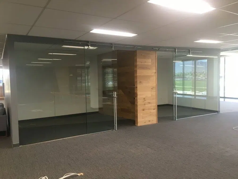 A spacious office with transparent walls and a sturdy wooden door.
