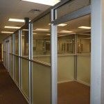 Glass-walled hallway with doors in a commercial setting.