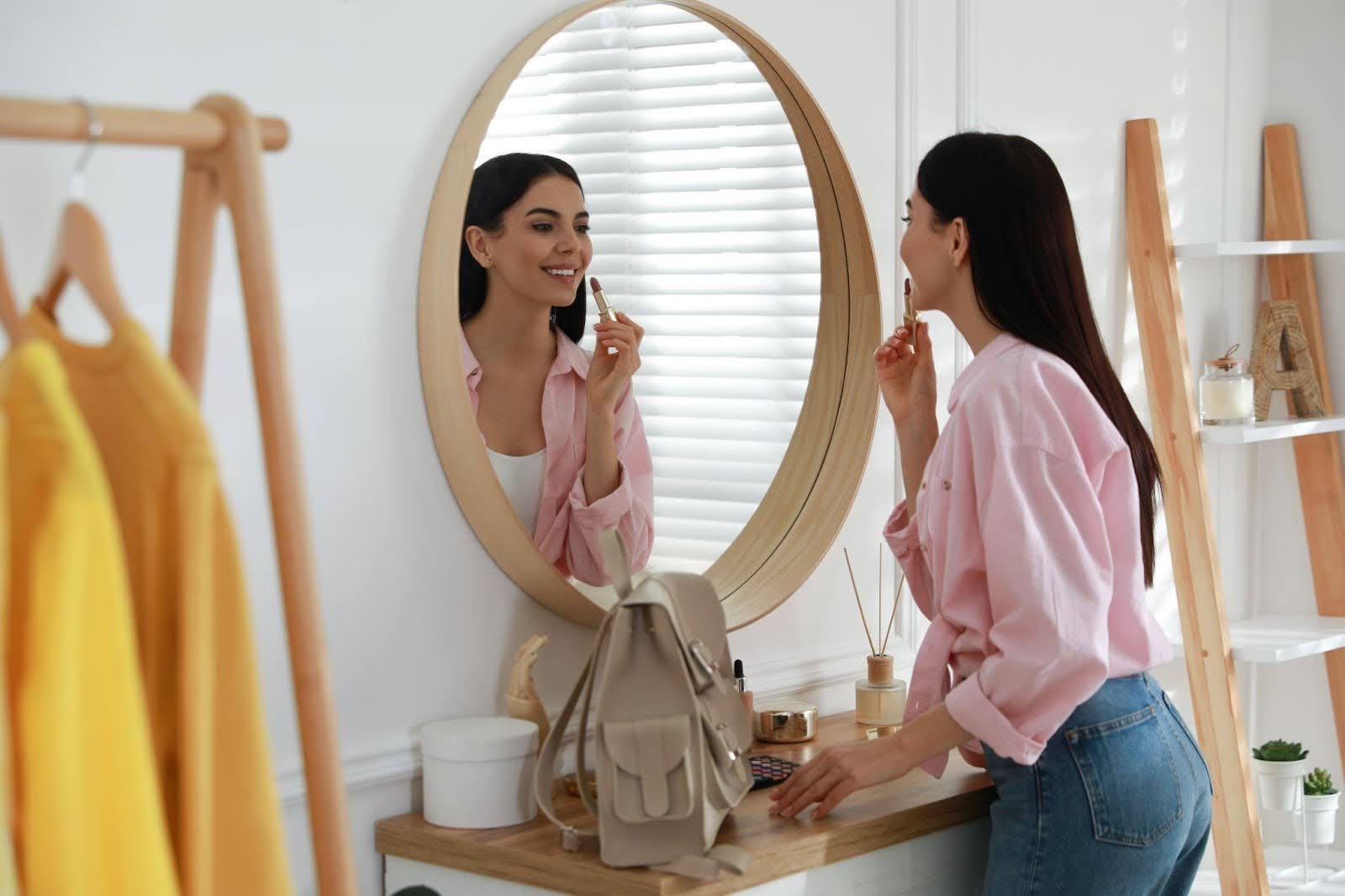 A woman observes herself in a mirror reflecting on her appearance with a focused demeanor