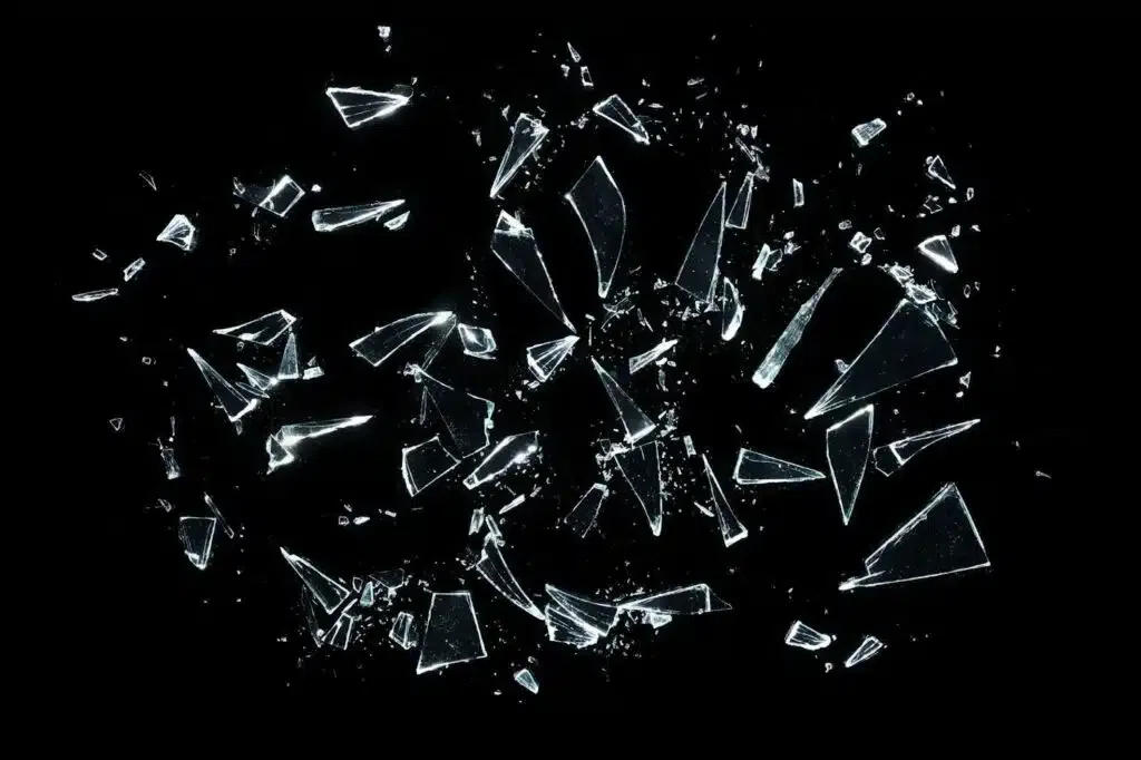 Shattered glass pieces on a black background reflecting light dramatically