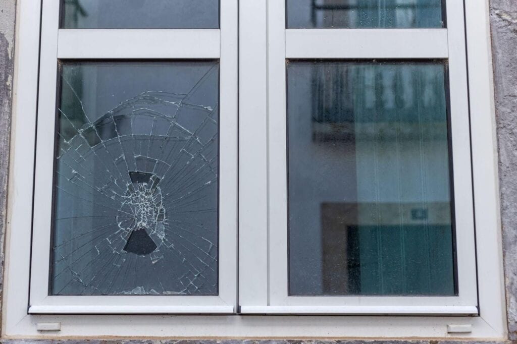 A broken window with shattered glass, highlighting structural vulnerability