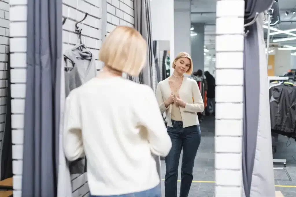 A woman browsing through clothes in a store, carefully examining different garments on display.