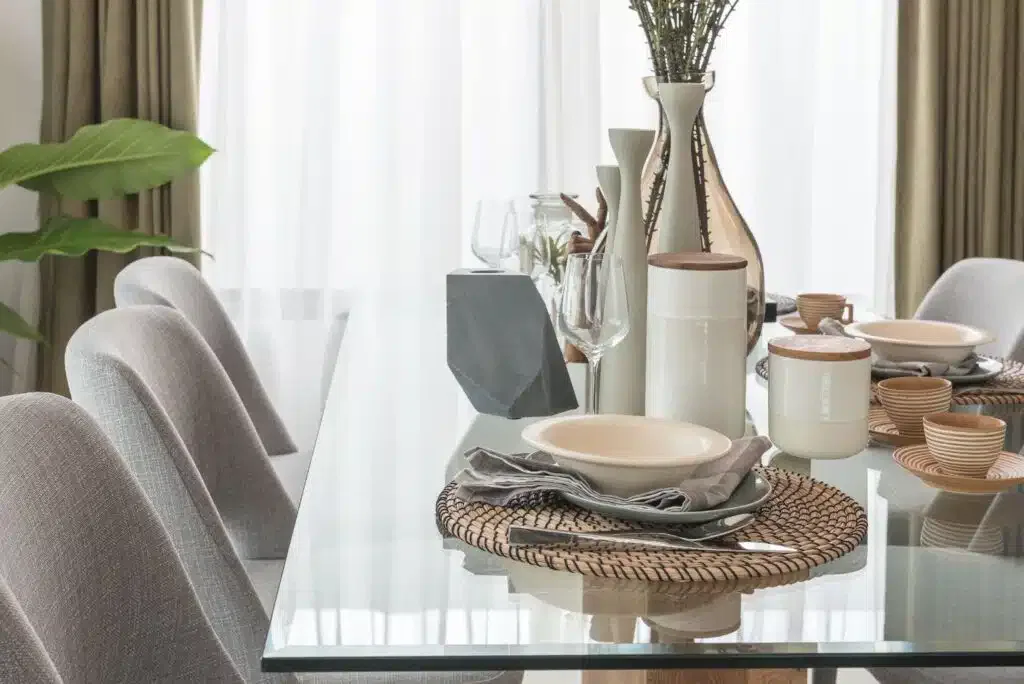A glass dining table adorned with a vase of flowers, showcasing a custom glass table topper for an elegant dining experience.
