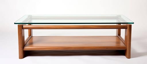 A glass top table featuring wooden legs and a lower shelf, elegantly designed for modern interiors