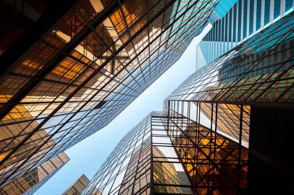View from the ground looking up at tall buildings against a clear blue sky