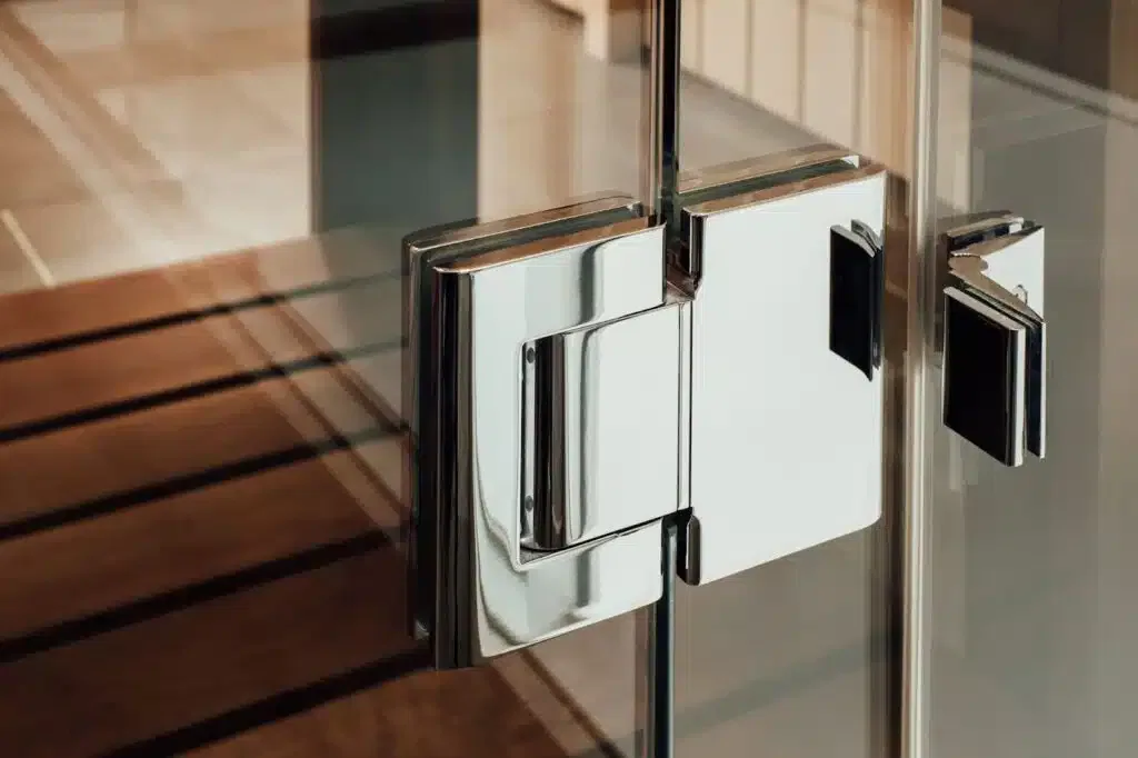 Close-up of a modern glass door hinge and handle.