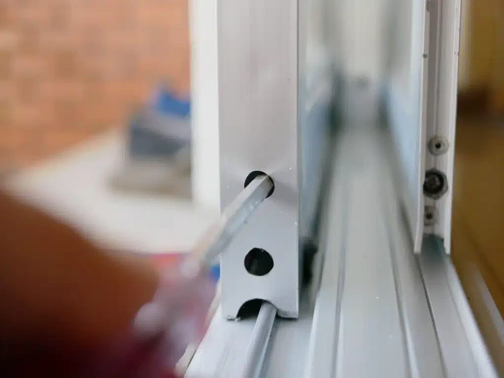 A person using a screwdriver to open a window focusing on the tool and their hand in action