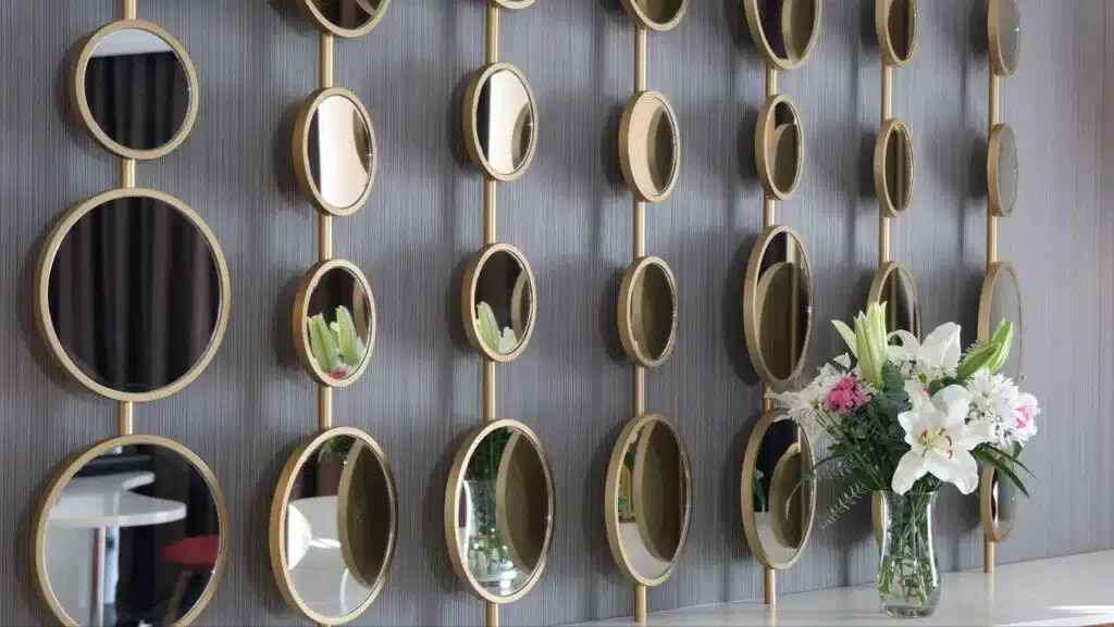 A decorative wall featuring multiple mirrors and a vibrant vase filled with fresh flowers