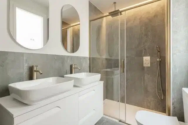 A modern bathroom in a new apartment featuring a sleek sink shower and neutral-colored tiles