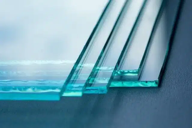 A stack of clear glass sheets neatly arranged on a wooden table surface