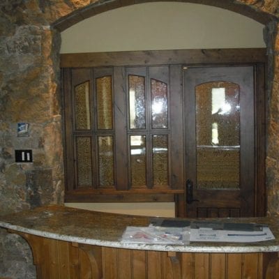 A kitchen with a stone counter top and a wooden door.