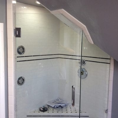 A glass shower door with a modern shower head inside a contemporary bathroom