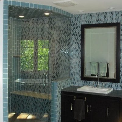 A bathroom with blue tile and a shower.
