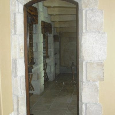 A stone archway leading to a home's entrance, framed by a wooden door.