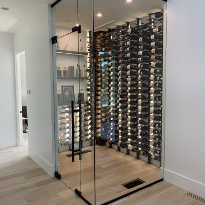 A wine room with a glass wall and a bed.