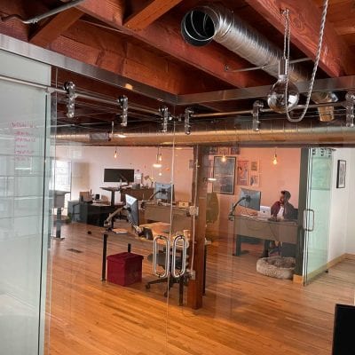 A spacious office with transparent walls and polished wooden floors.