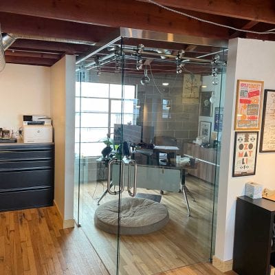 A spacious office with a desk and a transparent glass wall, providing an open and modern work environment.