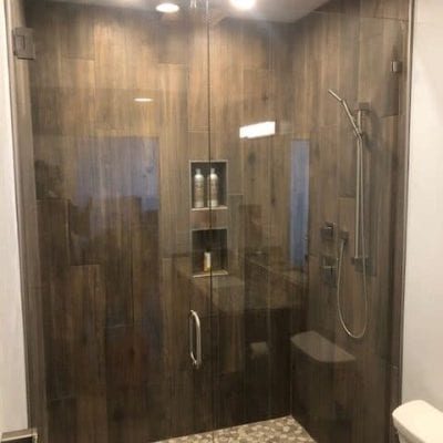 A bathroom with a glass shower door and a toilet.