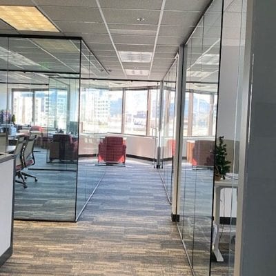 A spacious office with transparent walls and a well-organized desk.