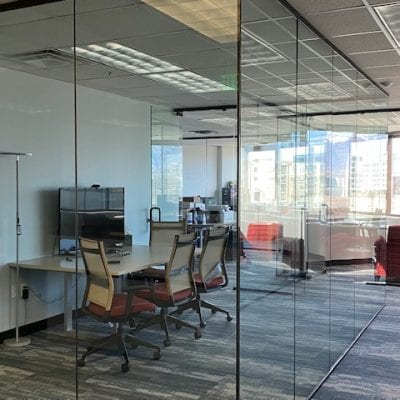 Modern office with glass walls, desk, chairs.
