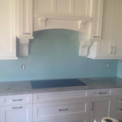 A kitchen with white cabinets and blue glass, creating a modern and sleek design.
