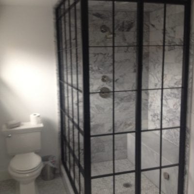 A modern bathroom with a transparent shower door and a toilet.