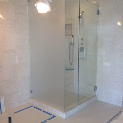A modern bathroom with a transparent shower door and tiled floor.
