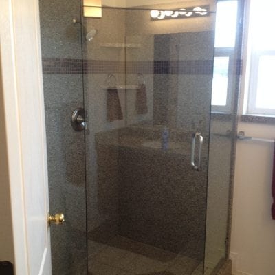A bathroom with a glass shower door and a toilet.