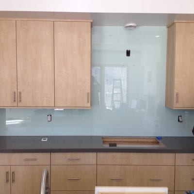 A man standing in front of kitchen cabinets.c