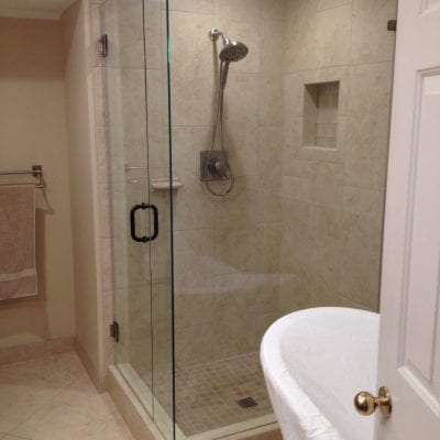 A bathroom with a glass shower door and a tub.