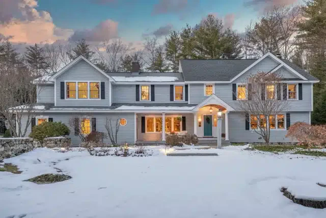 A snow-covered home with a clear driveway, surrounded by a blanket of white snow on the ground.